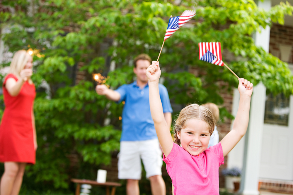 little-girl-holding-flags-4th-of-july-custom-lawn-care-kansas-city